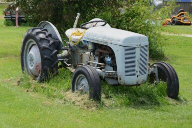 An old grey tractor sits in a field.